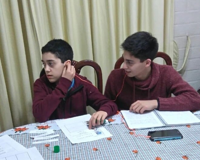 Carlos y Francisco estudiando juntos en la mesa de su casa
